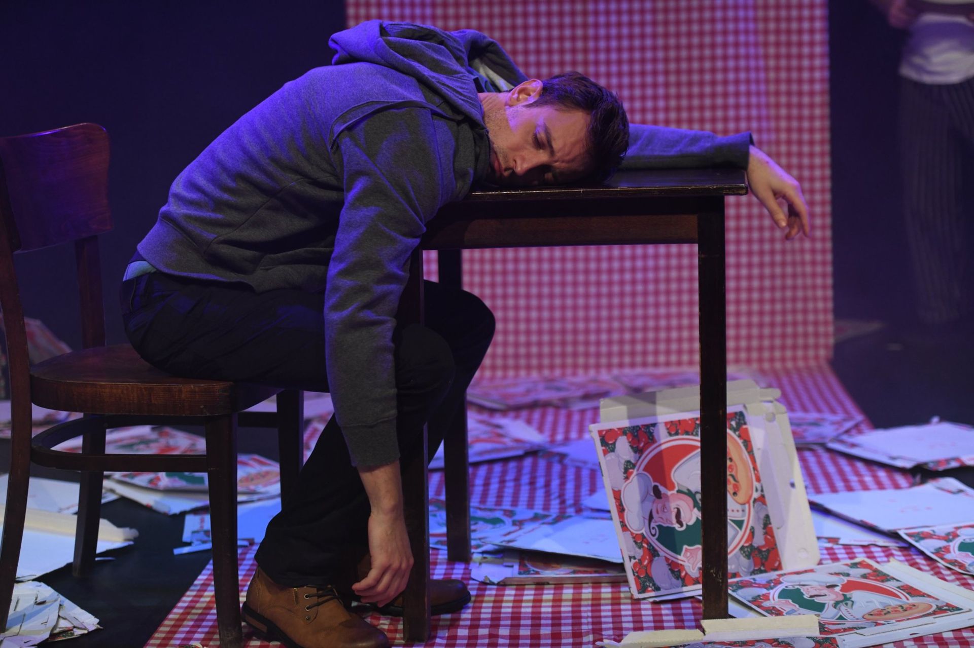 Romeo ligt met zijn hoofd op de tafel tussen de pizzadozen